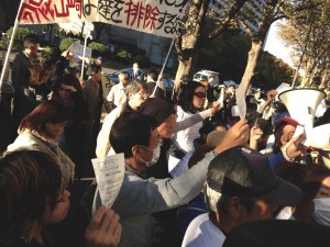 「傍聴させろ！」。当選券を掲げて抗議する被告本人と支持者ら。（撮影／片岡伸行・編集部）