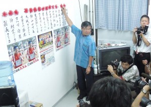 ９月７日に投開票された名護市議選挙で与党当選者氏名に花をつける稲嶺進市長。（撮影／本誌取材班）